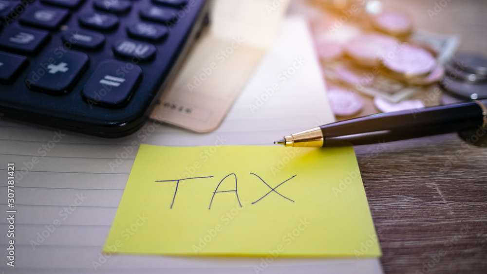 On the desk have coin pile, calculator, account book and Note paper have tax on it. Concept Planning for spending and accumulating money Including paying taxes. On the desk have coin pile, calculator, account book and Note paper have tax on it. Concept Planning for spending and accumulating money Including paying taxes.