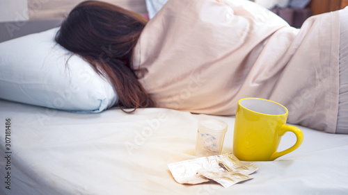 In the bedroom on the bed With a yellow glass of water along with the medicine There is a woman lying near. Concept Take medicine in the morning.