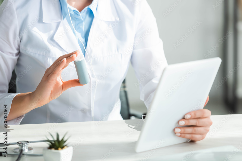 cropped view of doctor showing pills to patient on online consultation on digital tablet in office cropped view of doctor showing pills to patient on online consultation on digital tablet in office