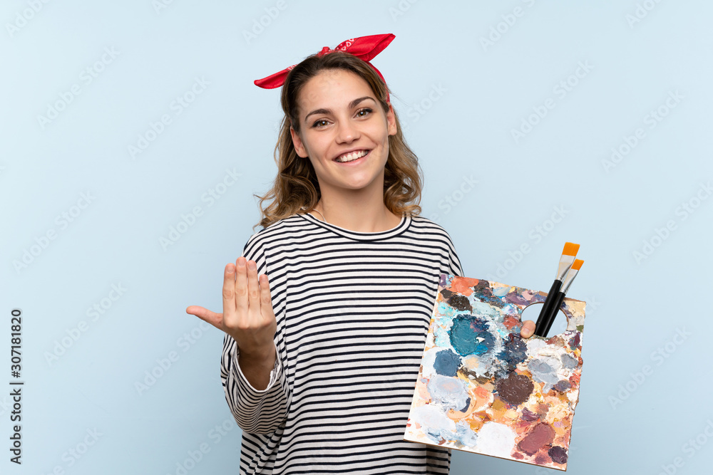 Φωτογραφία Young artist woman holding a palette over isolated blue background inviting to come with hand