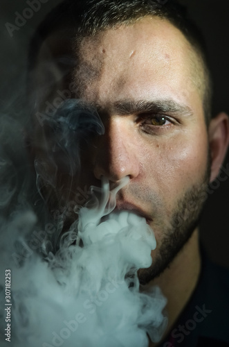 Man Vaping an Electronic Cigarette. Vaper Hipster Smoke Vaporizer and Exhals Smoke Cloud.