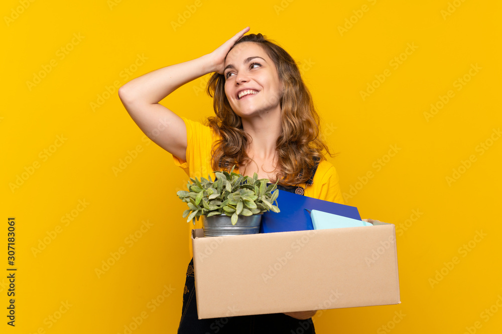 Young blonde girl making a move while picking up a box full of things has realized something and intending the solution Young blonde girl making a move while picking up a box full of things has realized something and intending the solution
