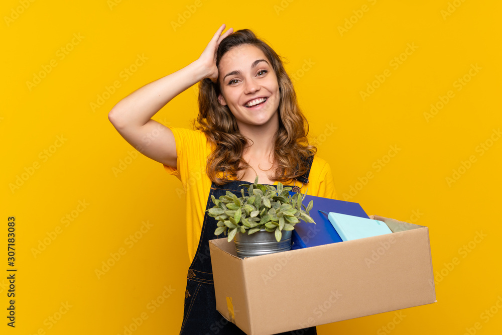 Young blonde girl making a move while picking up a box full of things with surprise and shocked facial expression Young blonde girl making a move while picking up a box full of things with surprise and shocked facial expression