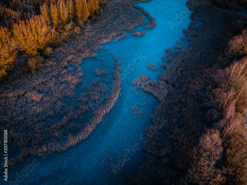 Aerial view of frozen river - sunrise first light on tree tops - rural Lithuania during first winter season days