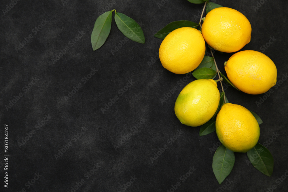 Juicy lemons on a branch with leaves on a black background. Organic fruits for a healthy diet. With copy space. Flat lay. Top view. Juicy lemons on a branch with leaves on a black background. Organic fruits for a healthy diet. With copy space. Flat lay. Top view.
