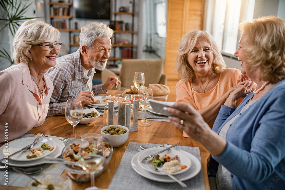 Group of cheerful senior friends having fun at dining table.