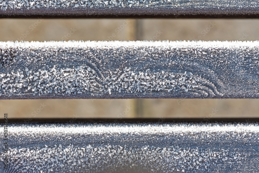Background of part a wooden bench surface covered with hoarfrost, frost, morning sunlight. Rime. Late fall.