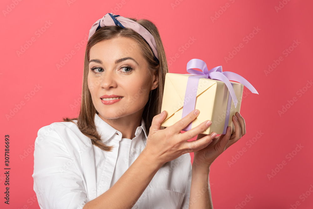 attractive and smiling woman holding gift isolated on pink attractive and smiling woman holding gift isolated on pink