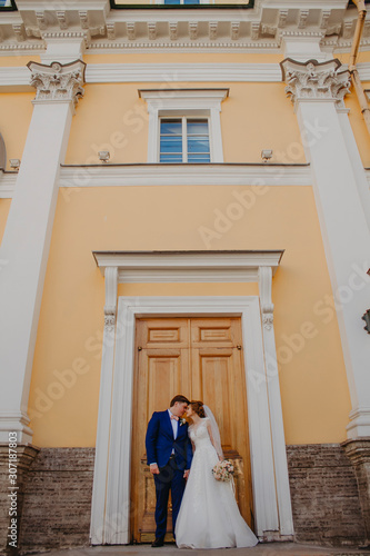 The bride and groom kiss near a beautiful building © Yuliya Timofeeva
