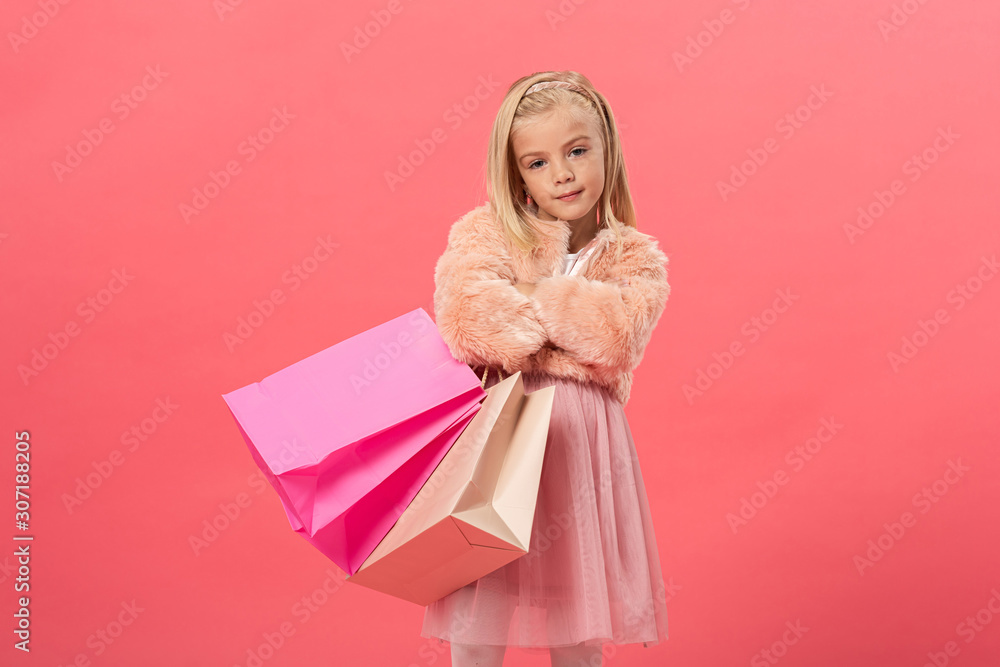 cute kid with crosses arms holding shopping bags isolated on pink cute kid with crosses arms holding shopping bags isolated on pink