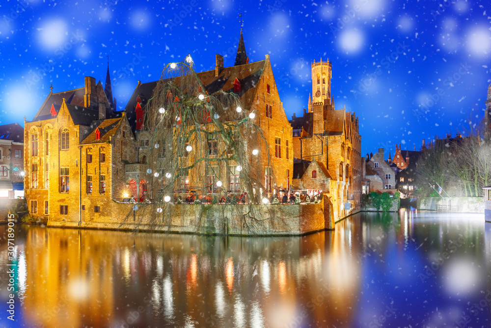 Fototapeta premium Medieval fairytale Old Town and tower Belfort from the quay Rosary, Rozenhoedkaai, in snowy evening, Bruges, Belgium