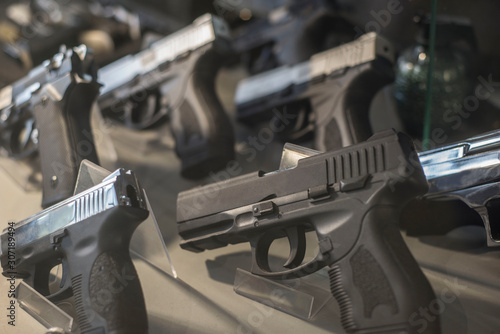 Black pistols behind the glass of a weapon store counter. Unusual look photo