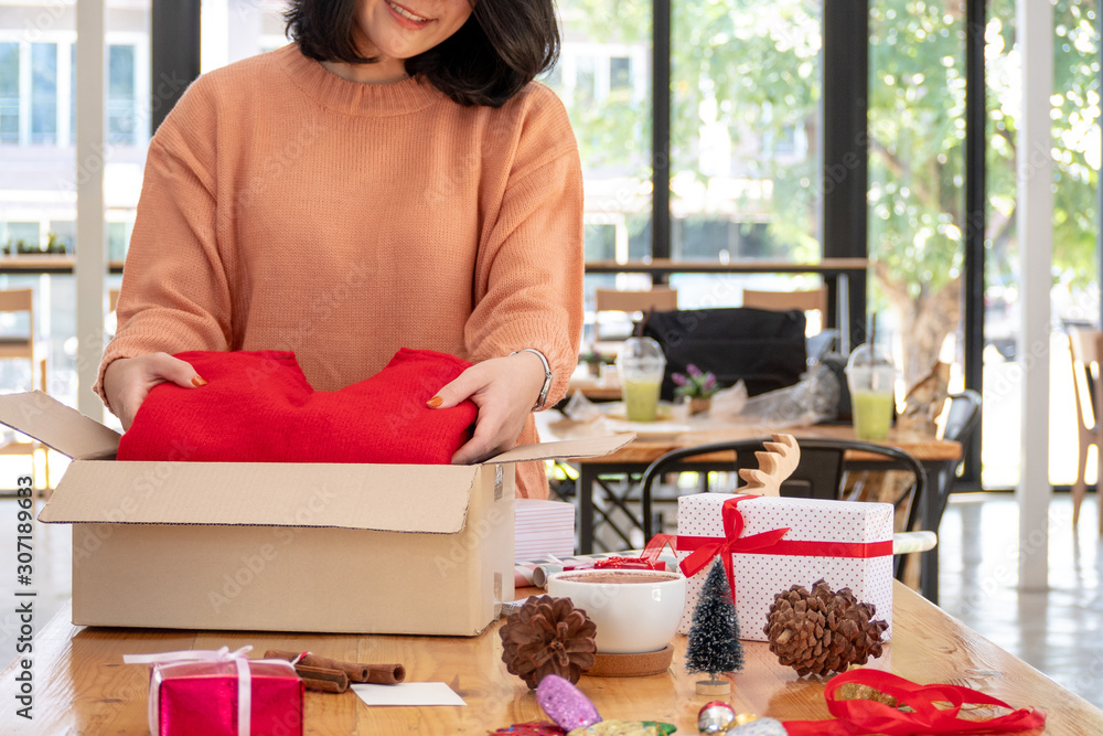 young asian woman packing red sweater for wrapping christmas or birthday present gift box young asian woman packing red sweater for wrapping christmas or birthday present gift box