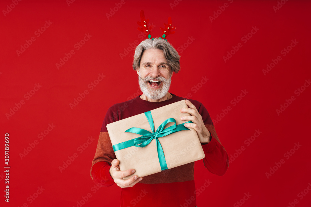 Portrait of gray-haired old man in sweater holding Christmas gift box Portrait of gray-haired old man in sweater holding Christmas gift box
