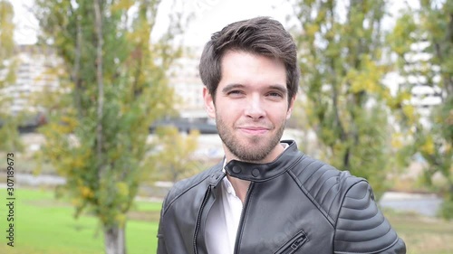 Young and attractive man looks at camera and smiles. Facial expressions.