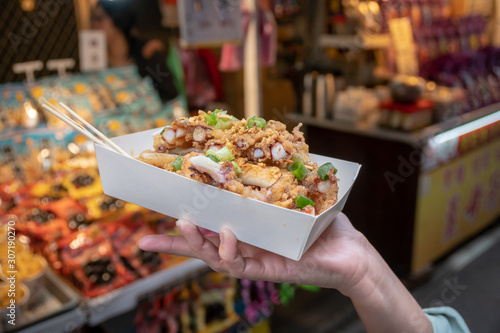 Selective focus of deep fried squid sliced  topped with spring onion on paper box.