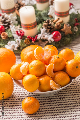 Tangerines and oranges on christmas table with advent wreath