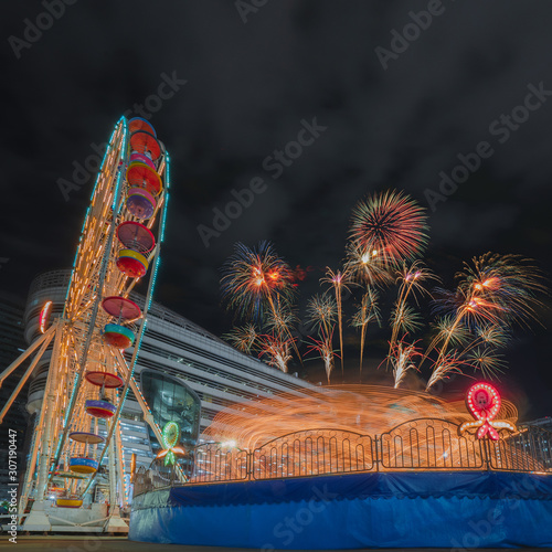 Ferris wheel and Octopus carousel ride with fireworks light up the sky at Siam carnival funfair at central plaza grand rama9 bangkok thailand,long exposure shot.