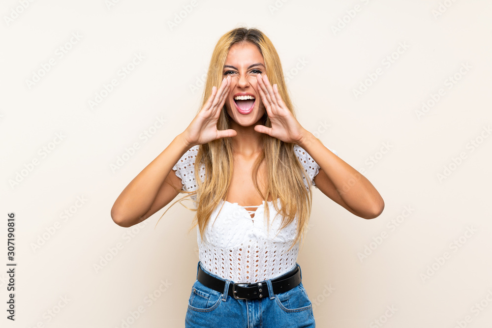 Young blonde woman over isolated background shouting with mouth wide open Young blonde woman over isolated background shouting with mouth wide open