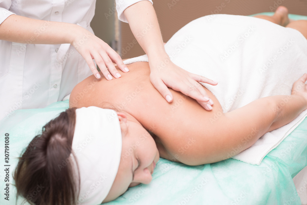 hands of a masseur girl, close up doing back massage to a young woman, in a spa salon