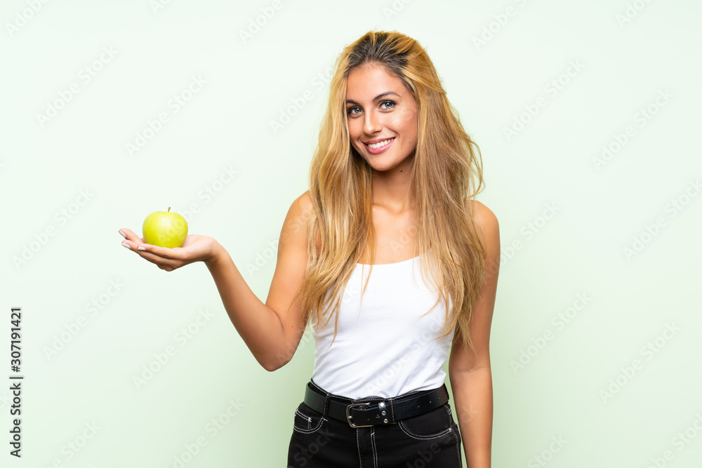Young blonde womanYoung blonde woman with an apple over isolated background Young blonde womanYoung blonde woman with an apple over isolated background