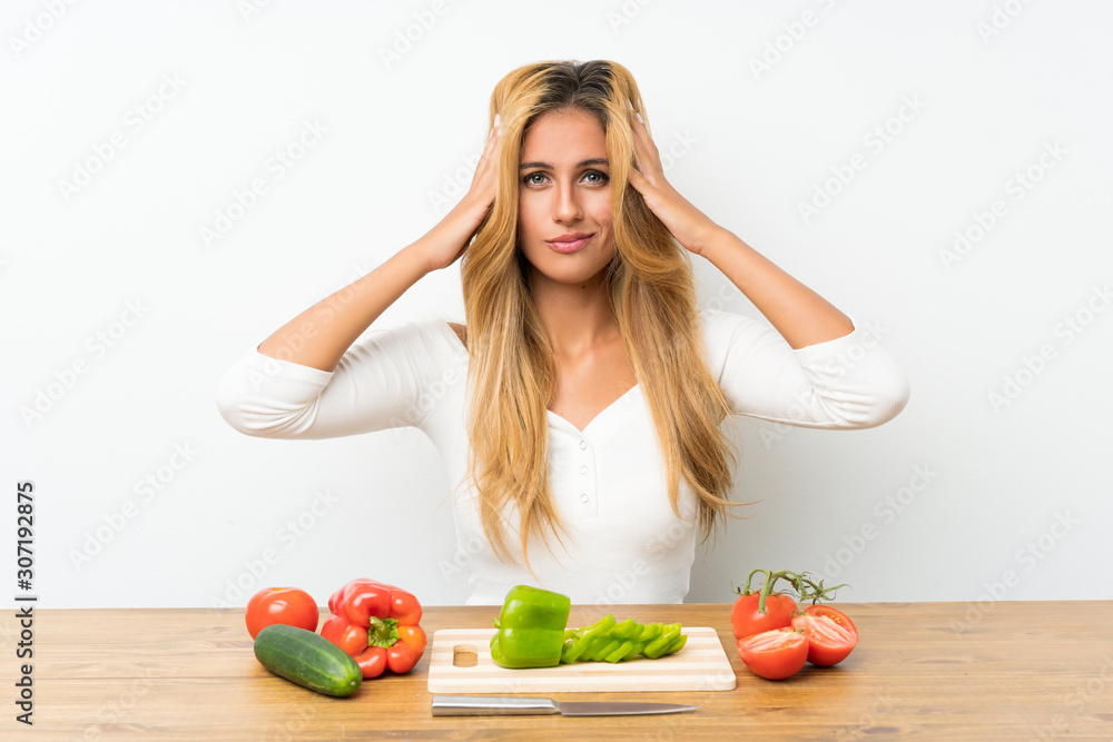 Young blonde woman with vegetables in a table unhappy and frustrated with something. Negative facial expression Young blonde woman with vegetables in a table unhappy and frustrated with something. Negative facial expression