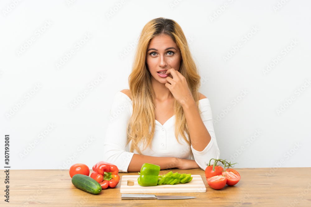 Young blonde woman with vegetables in a table nervous and scared Young blonde woman with vegetables in a table nervous and scared
