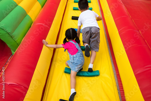 kids playing the air castle at temple festival. 8 years boy and 4 years girl are climbing slope wall to top of the wall. children love air castle because they feel relax and fun.