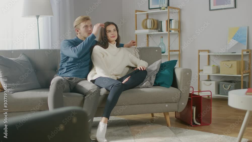Young Couple Use Augmented Reality, Swiping and Choosing Media Content to Watch in their Living Room. Girlfriend and Boyfriend. For Motion Tracking Video Editing, Tracking Points Added on Furniture Young Couple Use Augmented Reality, Swiping and Choosing Media Content to Watch in their Living Room. Girlfriend and Boyfriend. For Motion Tracking Video Editing, Tracking Points Added on Furniture