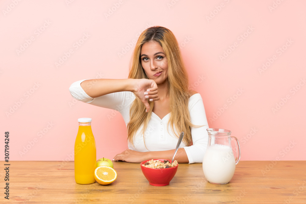 Young blonde woman having breakfast milk showing thumb down sign