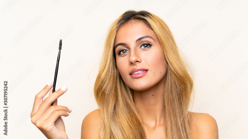 Young blonde woman applying mascara with cosmetic rush Young blonde woman applying mascara with cosmetic rush