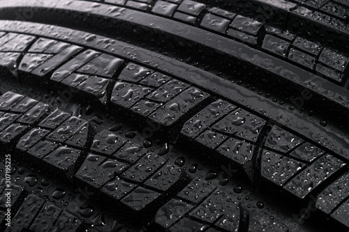 Surface of a new and modern multi season car tyre with water drops. Studio shot (high details)