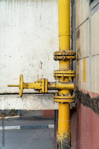 Rusty yellow gate valve with flywheel and flanges on the pipe with welds