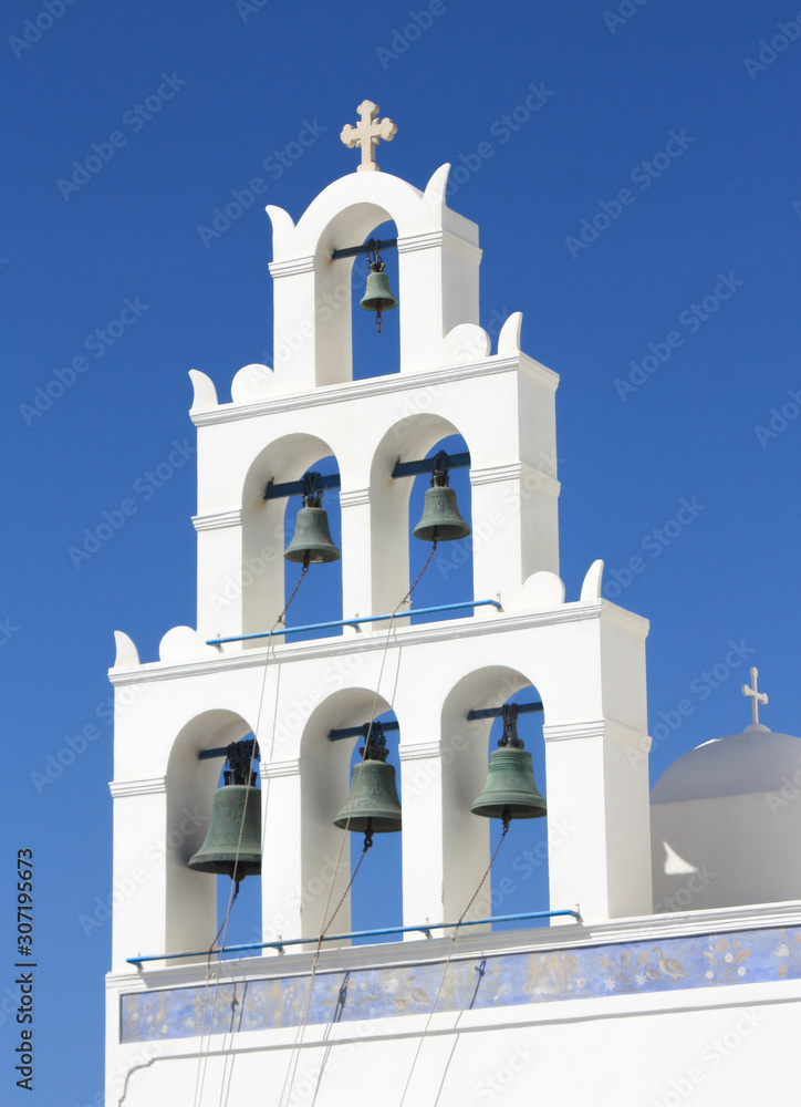 Oia, Santorini Greece scene of white church towers with 6 bells against blue sky
