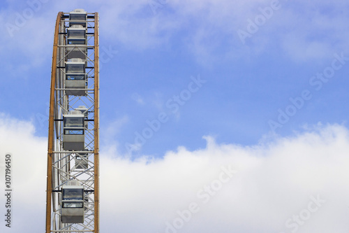 view from the side of a ferris wheel made of glass and metal against a blue sky.