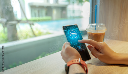 Close up of Woman using a phone with eSIM technology. Mobile device with a chip on a circuit board art.eSIM(Embedded SIM) - electronic sim phone new mobile communication technology.