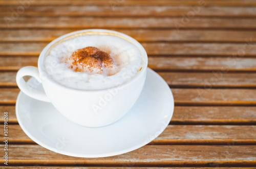 close up modern coffee the cappuccino on wood background with coffee bubble foam pattern and texture in white cup looking and feel so delicious on glasses table in coffee shop.