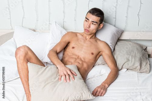 Young handsome man rest in bed. Sexy naked guy is resting