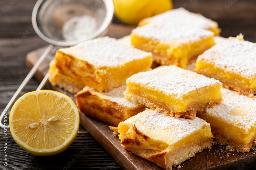 Homemade lemon bars with shortbread crust, on wooden background. 