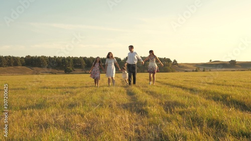 concept of a happy family. Children and mom are playing in meadow. mother and little daughter with sisters walking in park. Happy young family with child walking on summer field. happy family concept