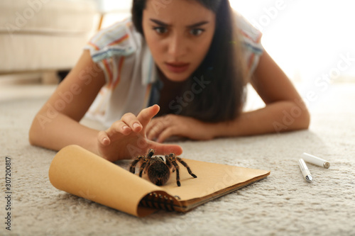 Obraz na płótnie Young woman and tarantula on carpet