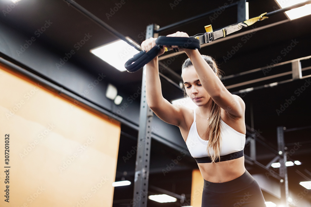 Spectacular young brunette sporty girl is engaged in the gym for building muscles and a beautiful figure. The concept of professional sports and taut body Spectacular young brunette sporty girl is engaged in the gym for building muscles and a beautiful figure. The concept of professional sports and taut body