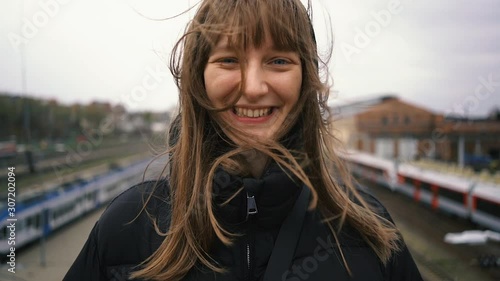 Portrait young laughing happy woman traveler on railway station waiting train.