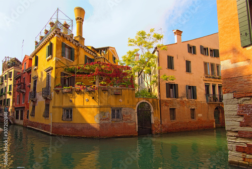Venice, Italy-September 28, 2019: Typical street corner in Venice. Ancient building with small garden and canal with turquoise water around the house