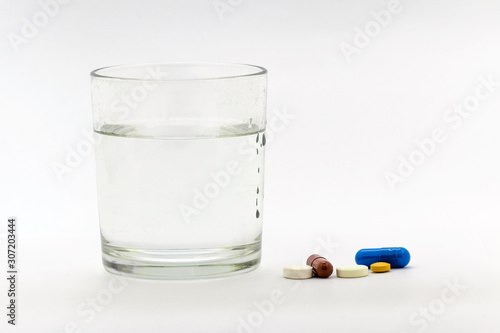 A glass of water next to the pills. It's time to take your medicine_
