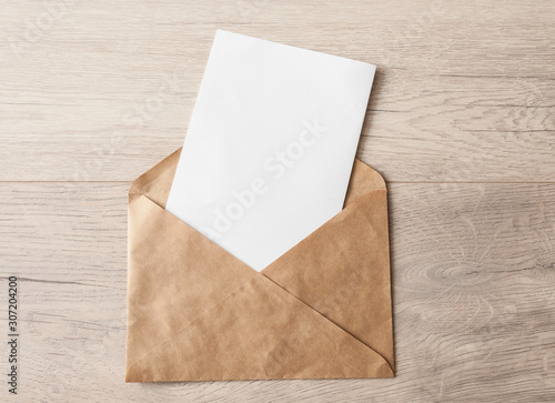 Blank paper envelopes on light wood table background.