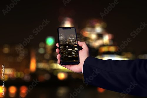 Hombre de negocios sacando una fotografía al skyline de Londres desenfocado y de noche