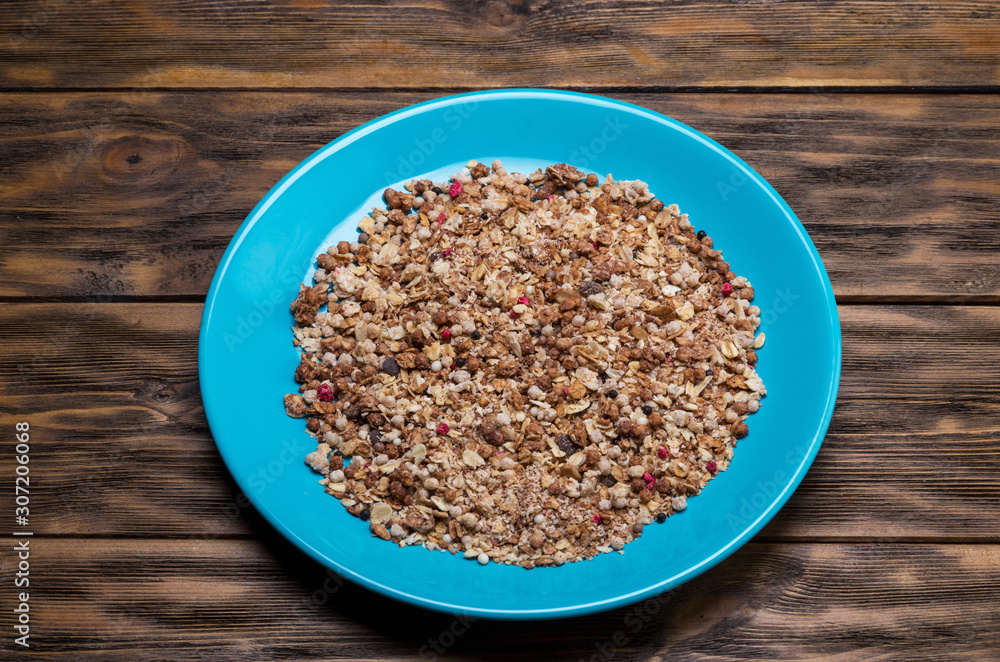 Muesli flakes in blue plate on wooden background Muesli flakes in blue plate on wooden background
