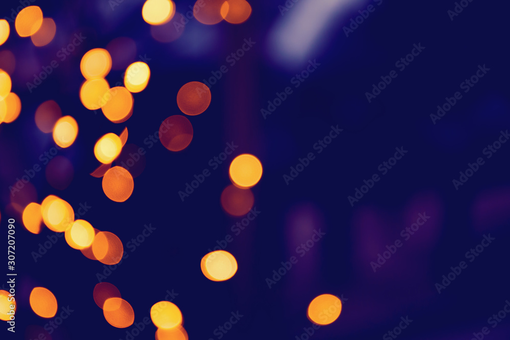 Defocused glittering background of golden garland christmas lights. Abstract blurry bokeh backdrop.