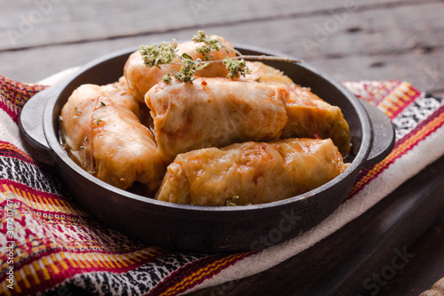 Meat in cabbage rolls in a black pan with  sauce on wooden background.  Asian cuisine top view